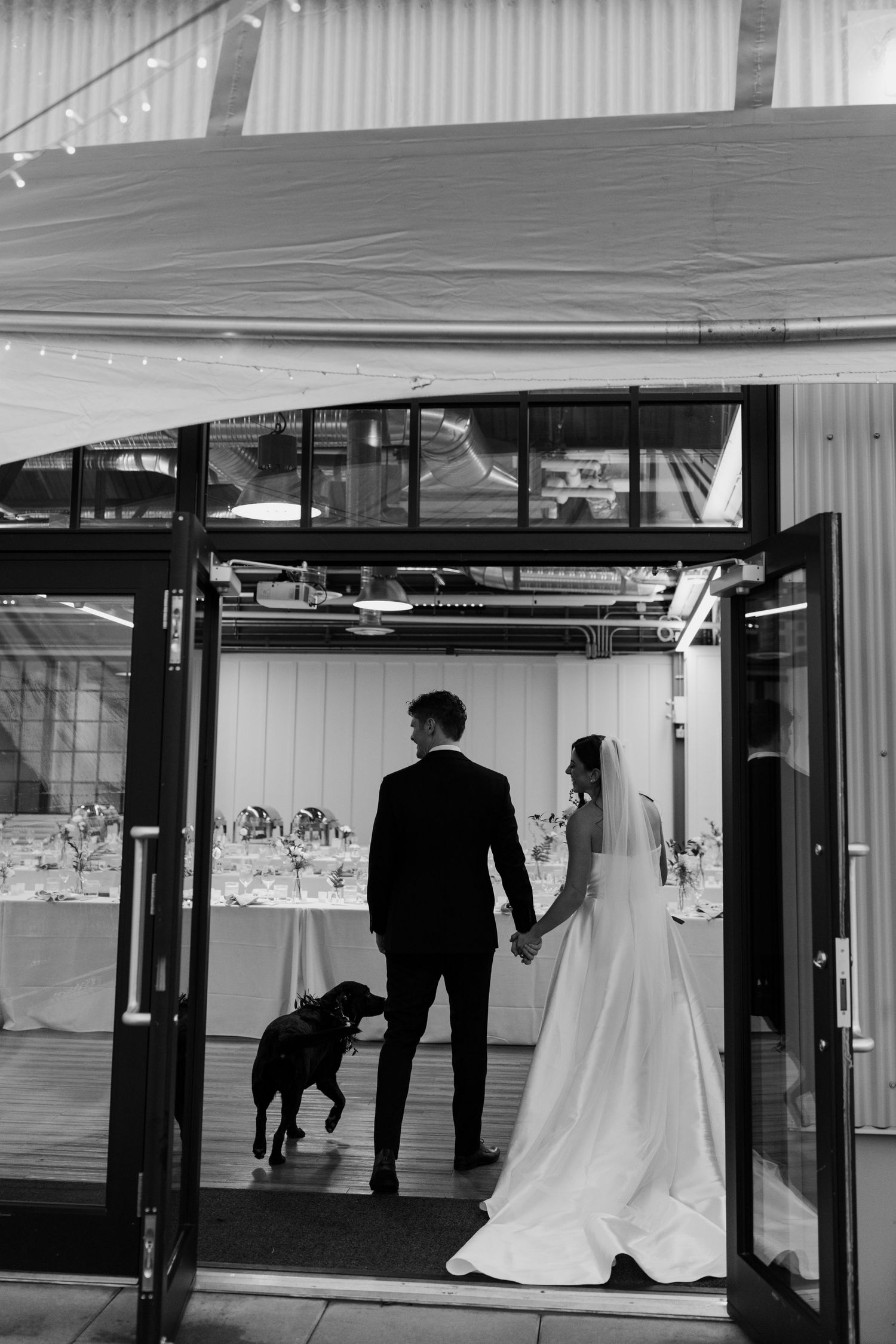 A wedding celebration inside a modern venue with glass walls and waterfront views.