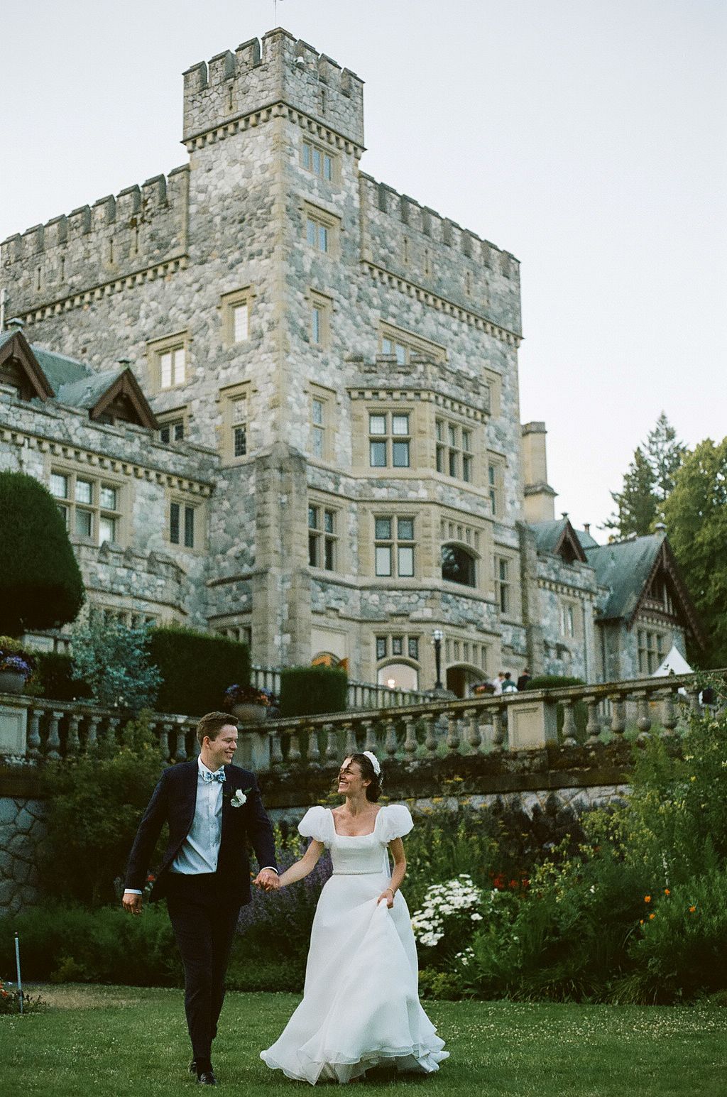 Wedding couple dancing in front of a majestic stone castle with Gothic architecture.