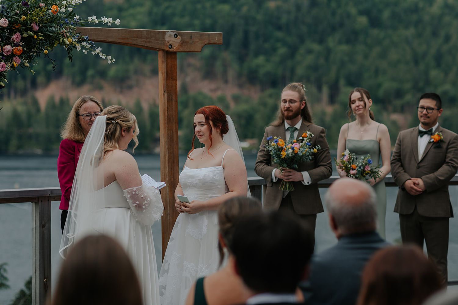 Wedding ceremony taking place on an outdoor deck with mountain and lake views.