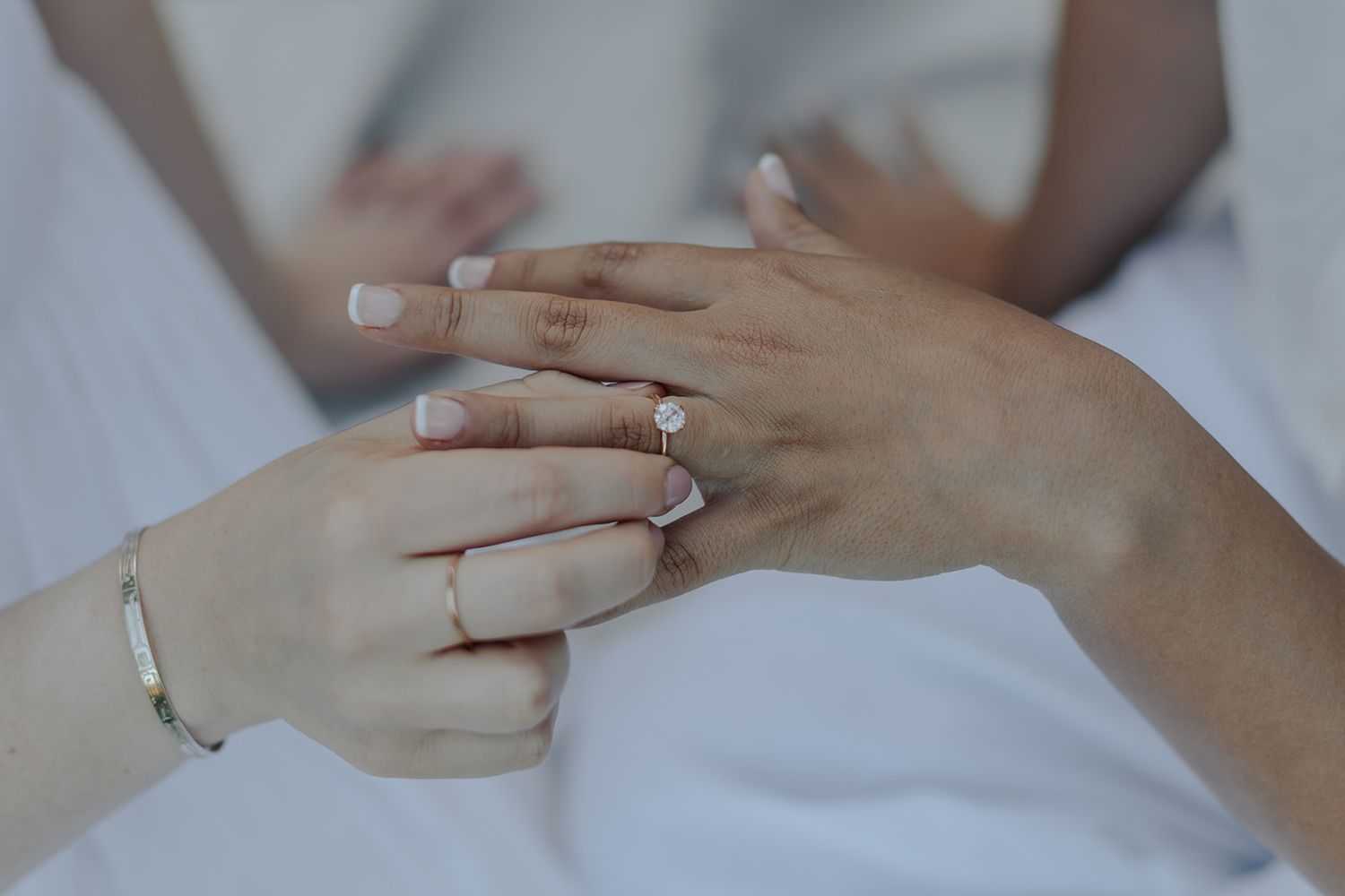Close-up of hands with an engagement ring on a white background showing a romantic proposal moment.