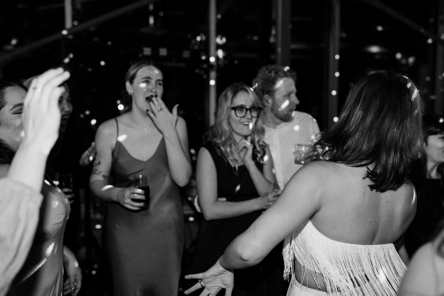 Crowded dance floor with party-goers enjoying music under dark atmospheric lighting.