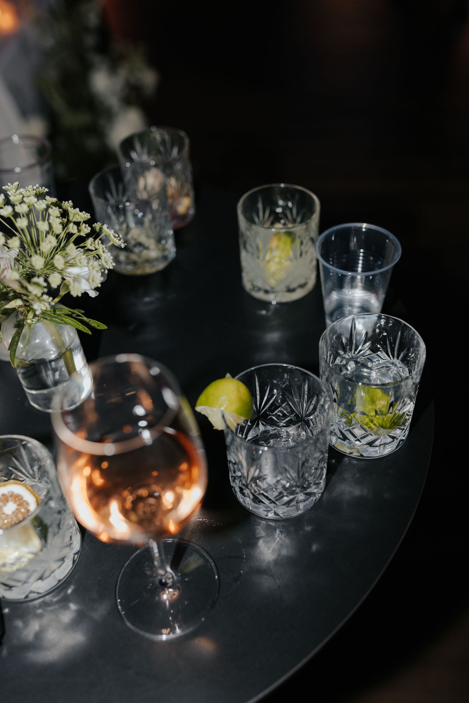 Elegant cocktail glasses with floral arrangements on a dark table setting.