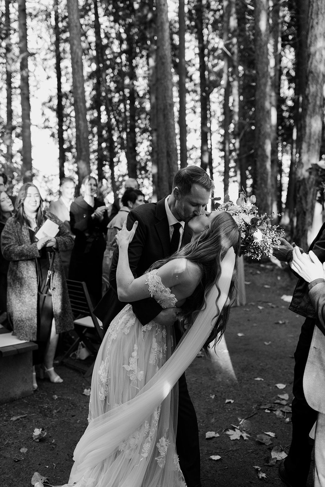 Wedding ceremony taking place in a serene forest setting with tall trees.