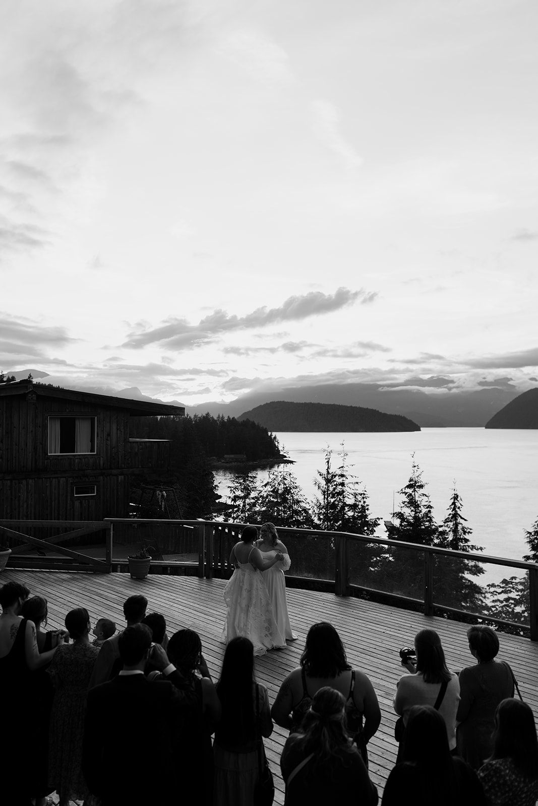 Black and white photo of a sunset wedding ceremony with mountain and water views.