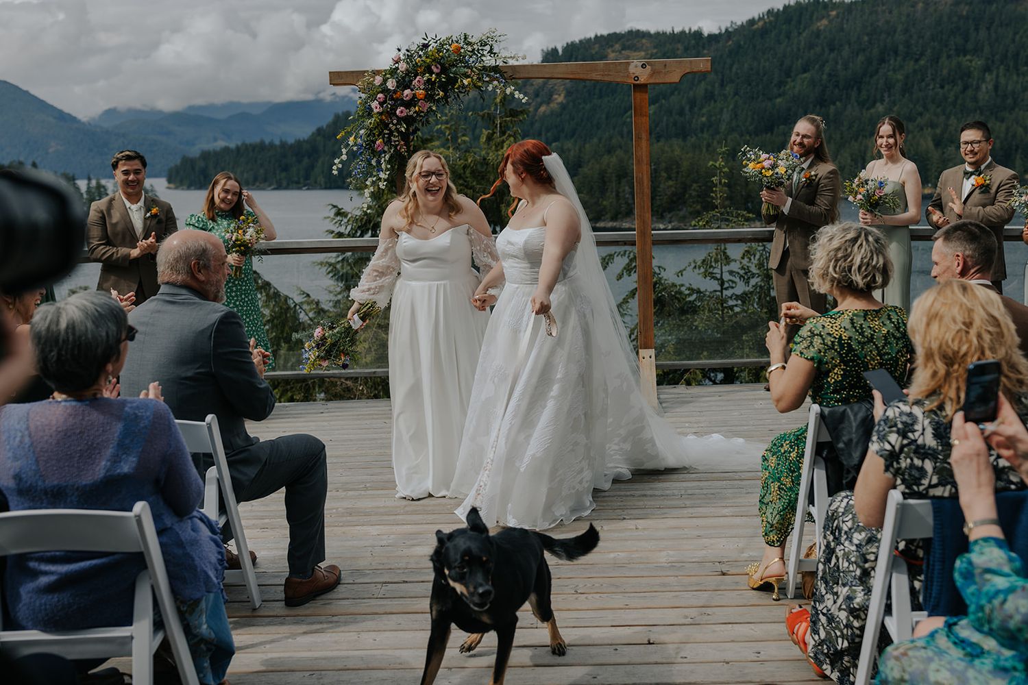 Wedding ceremony setup on a scenic mountain deck with wooden arch and white chairs.