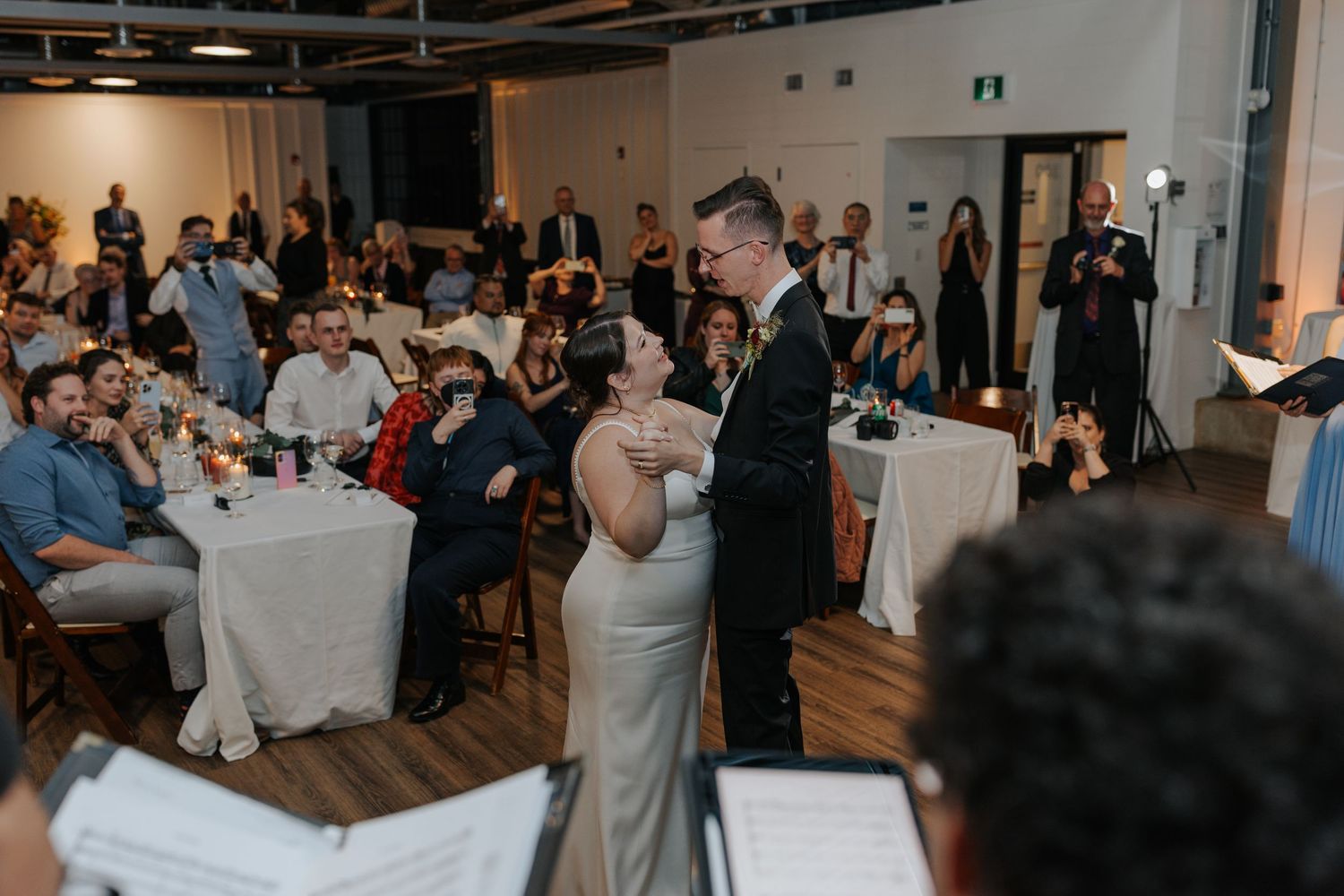 Modern wedding reception venue with white tables and industrial ceiling details.