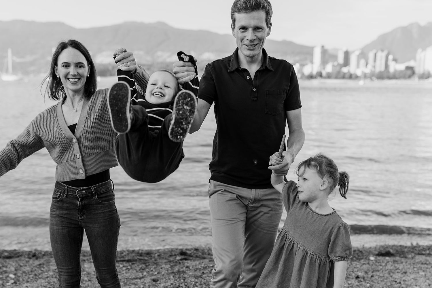 Black and white photos of family playing and laughing together at a coastal location.