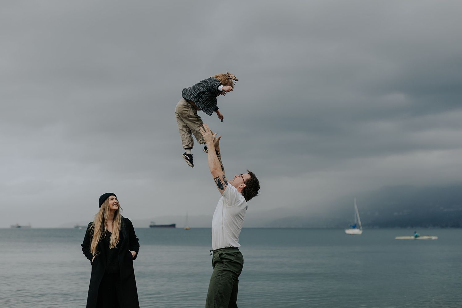 Playful family moments captured against moody coastal backdrop.