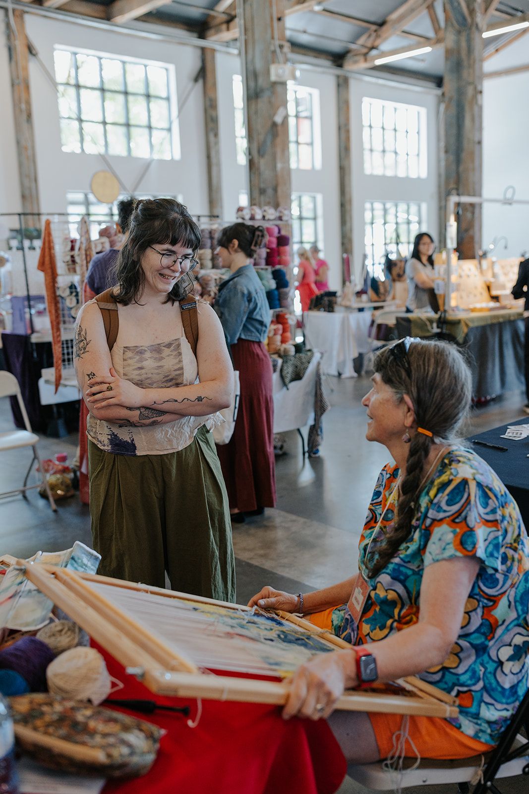 Guests interact at a craft workshop in an industrial-style venue with large windows.