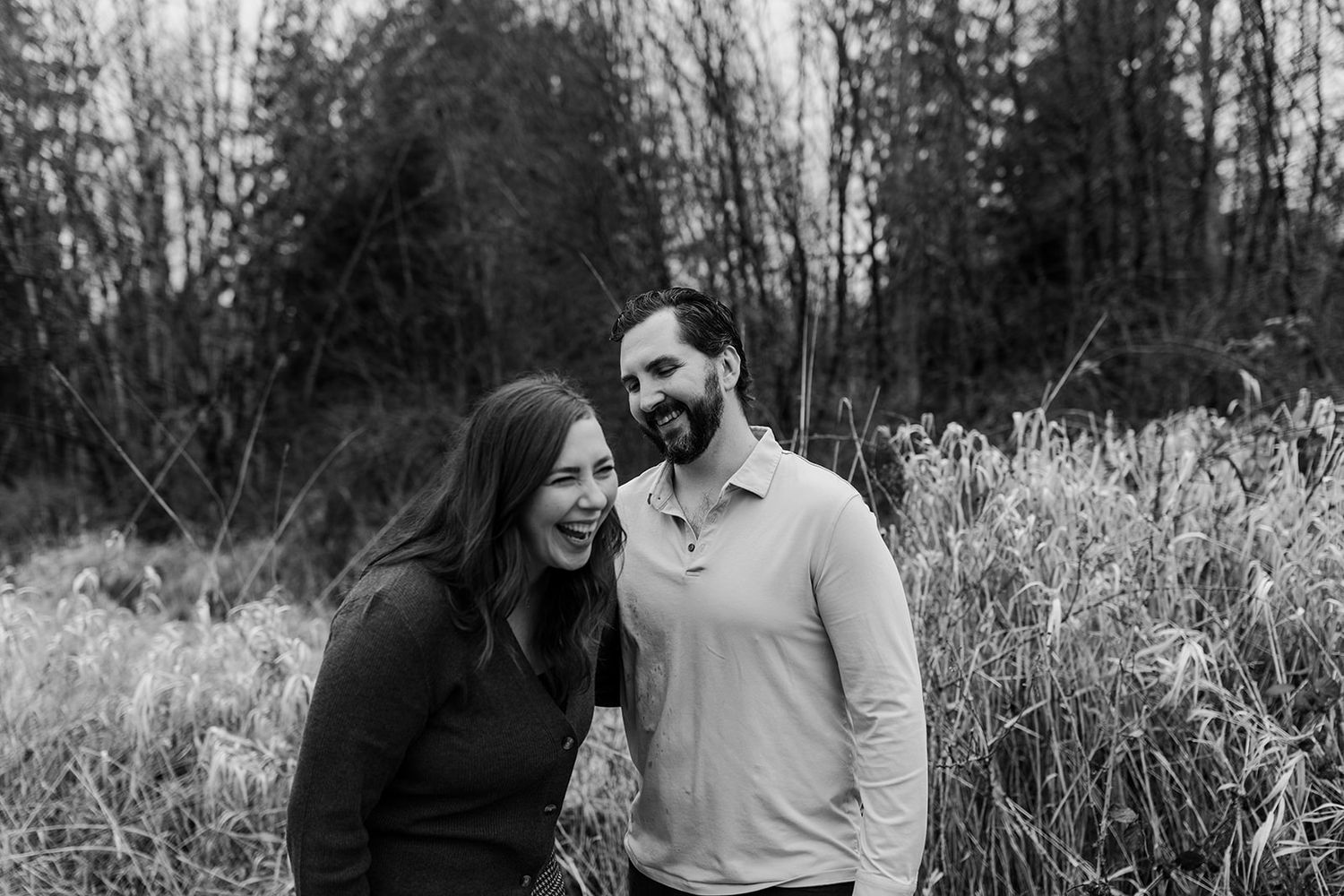 A couple laughs together in a black and white outdoor photo series.