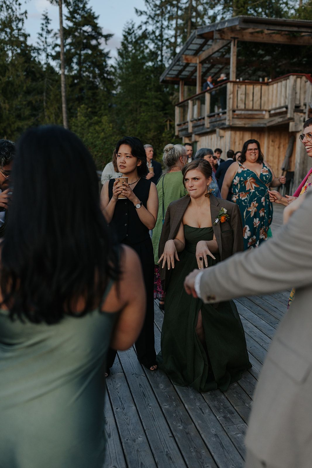 Evening wedding reception with guests in formal attire mingling on an outdoor deck.