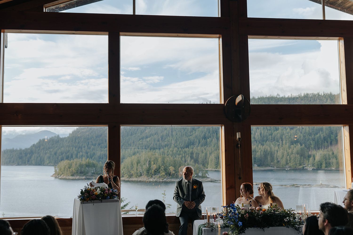 Rustic lodge interior with scenic waterfront views during a wedding celebration.