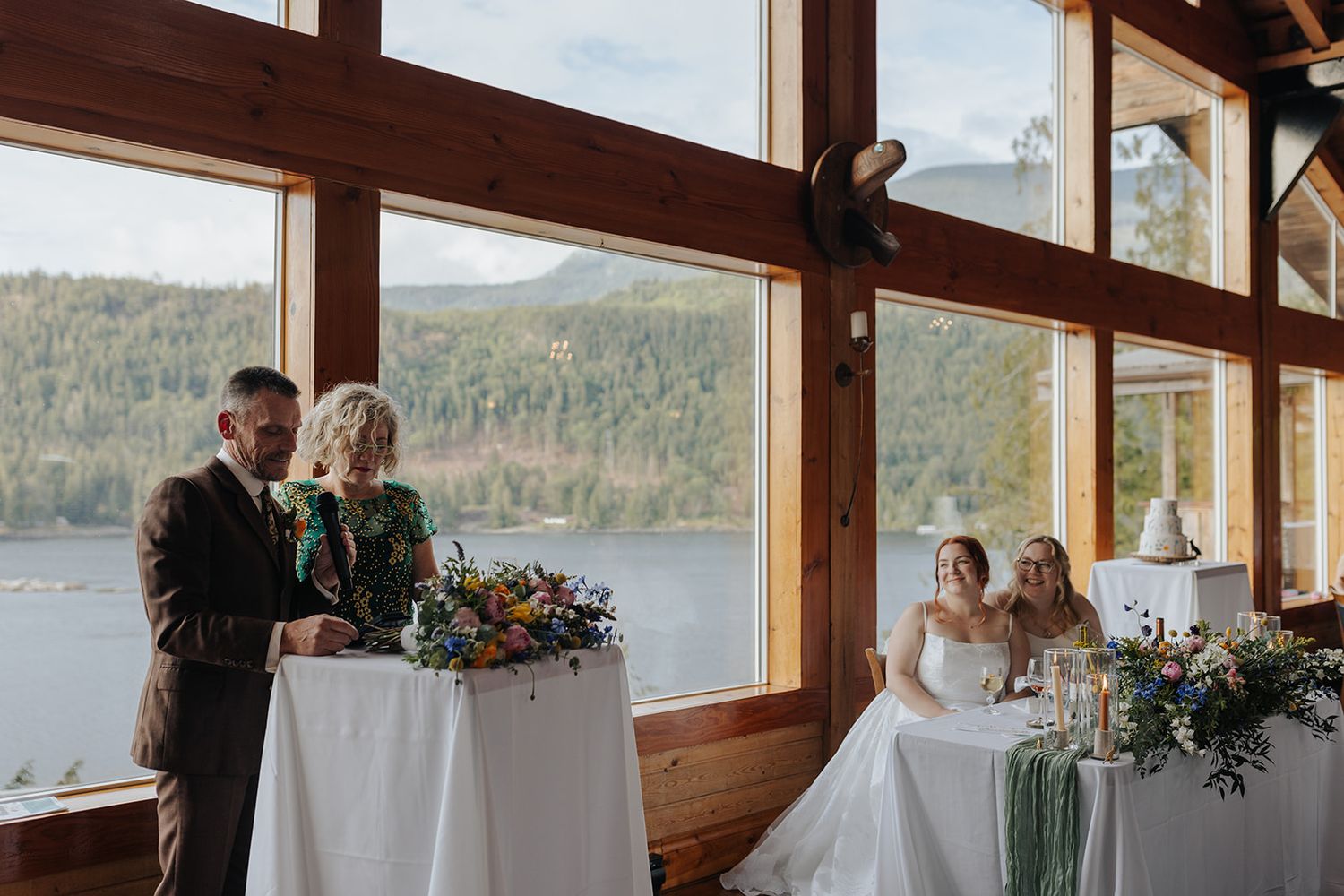 Wedding reception setup in a rustic wooden venue with panoramic mountain and lake views.
