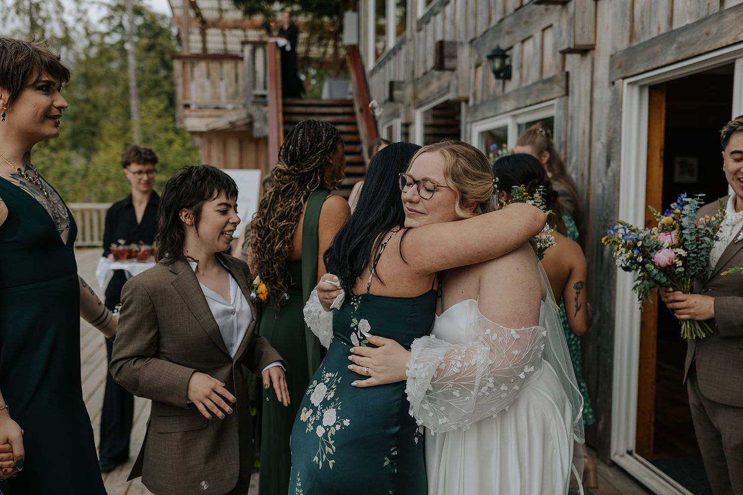 Joyful wedding celebration with guests embracing and laughing.