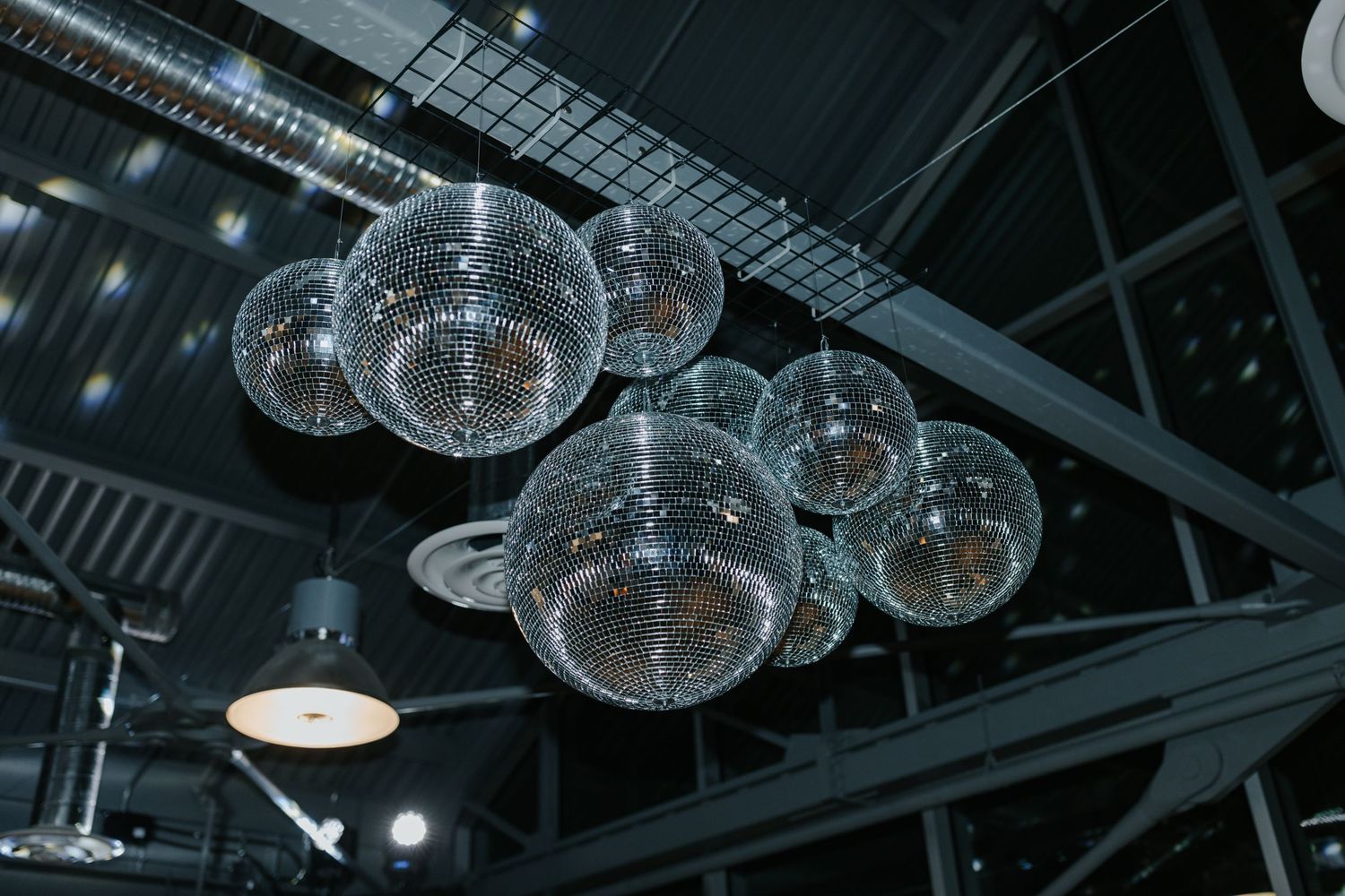 Modern disco balls hang from industrial ceiling creating elegant party atmosphere.