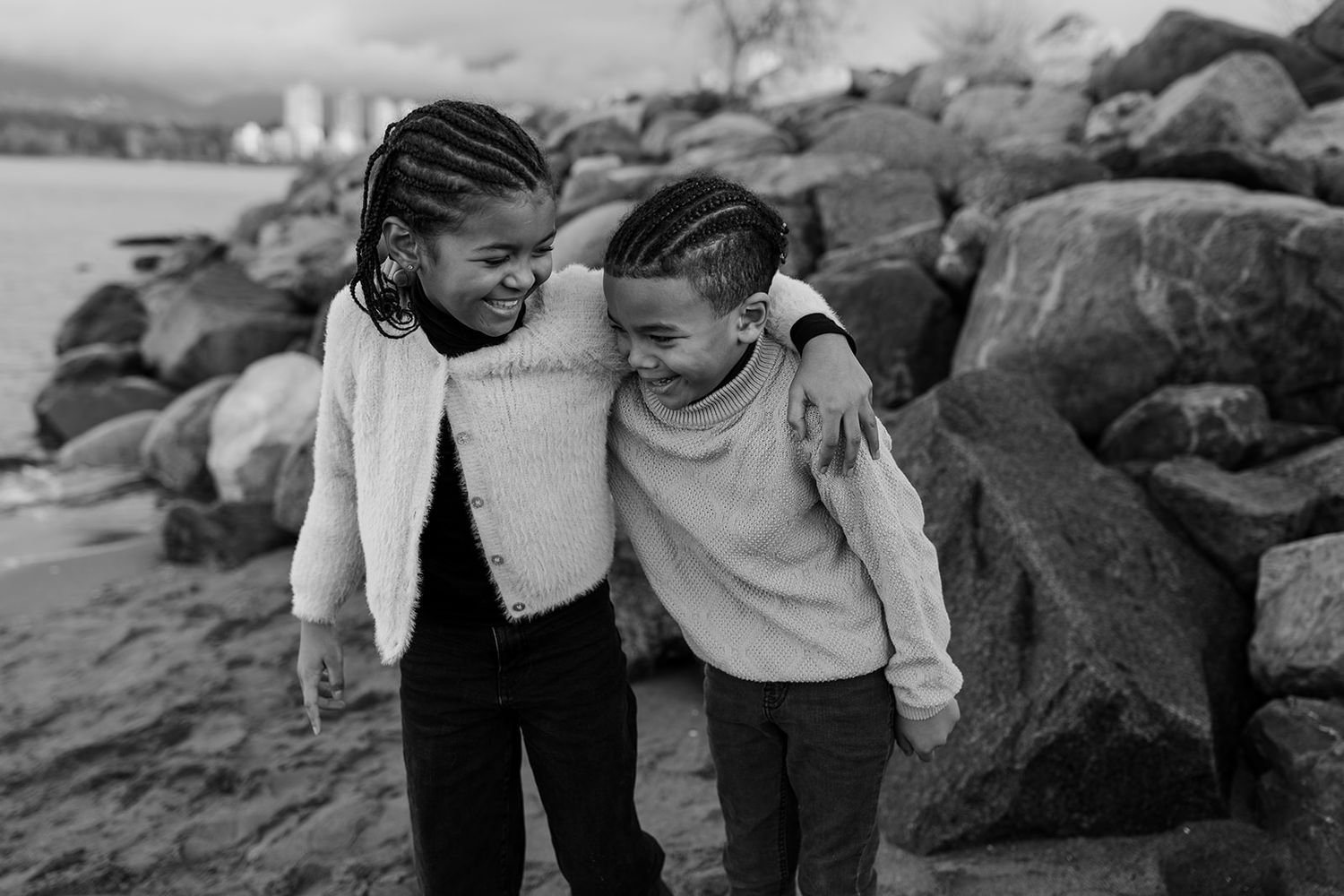 Black and white family portraits captured on rocky beach terrain.