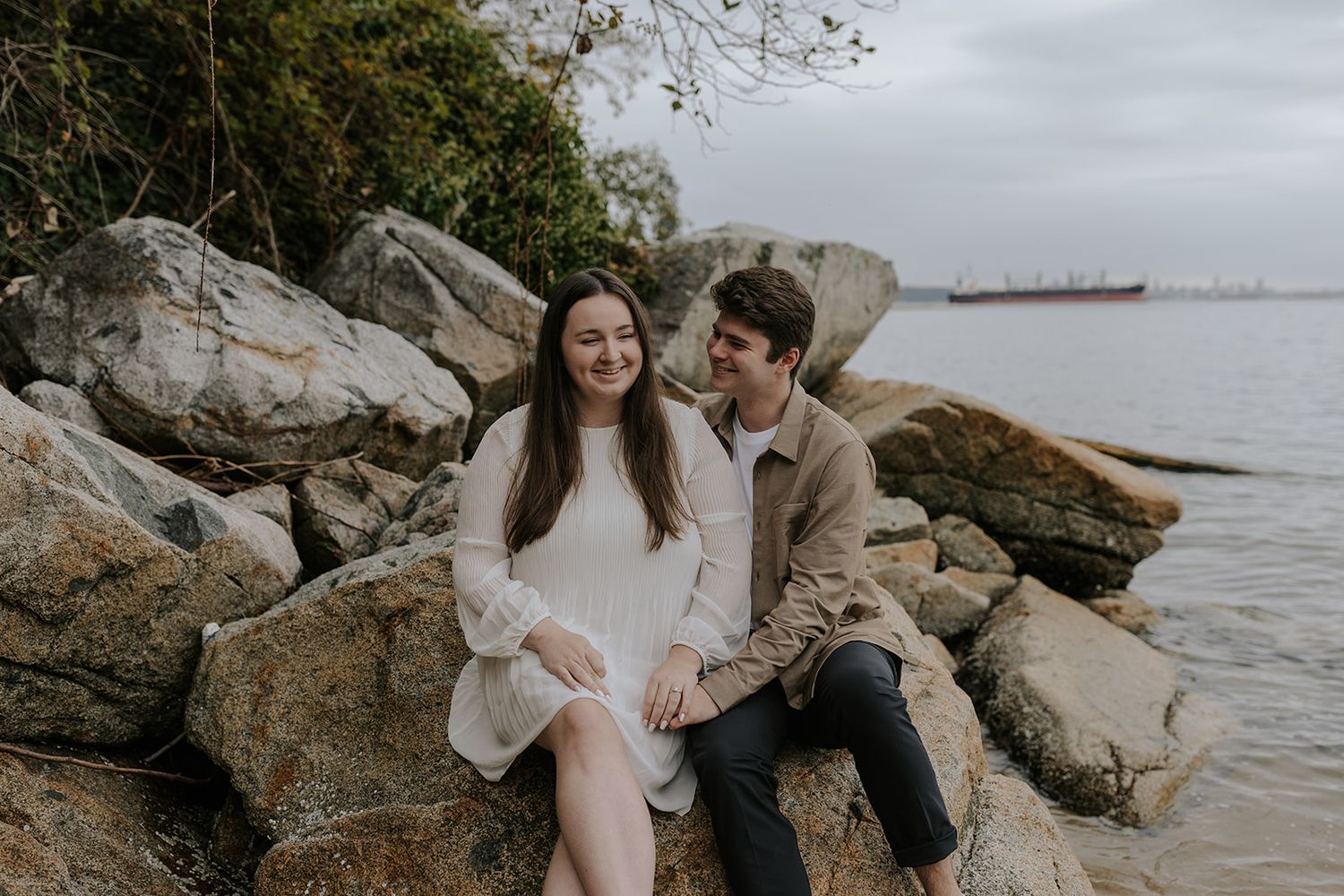 Romantic couple moment captured on a rocky beach shoreline.