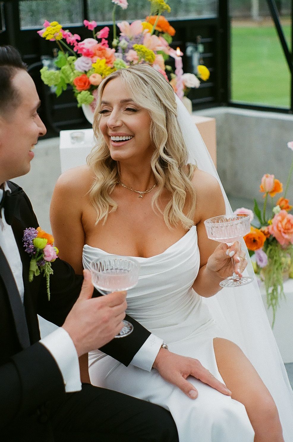 Candid moments between newlyweds during wedding reception with colorful floral decor.