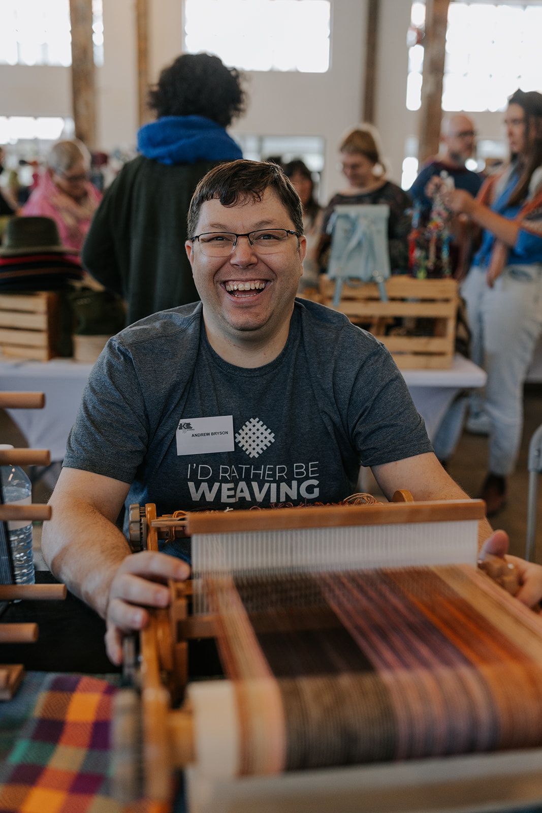 Person at a weaving loom working on a colorful textile project.