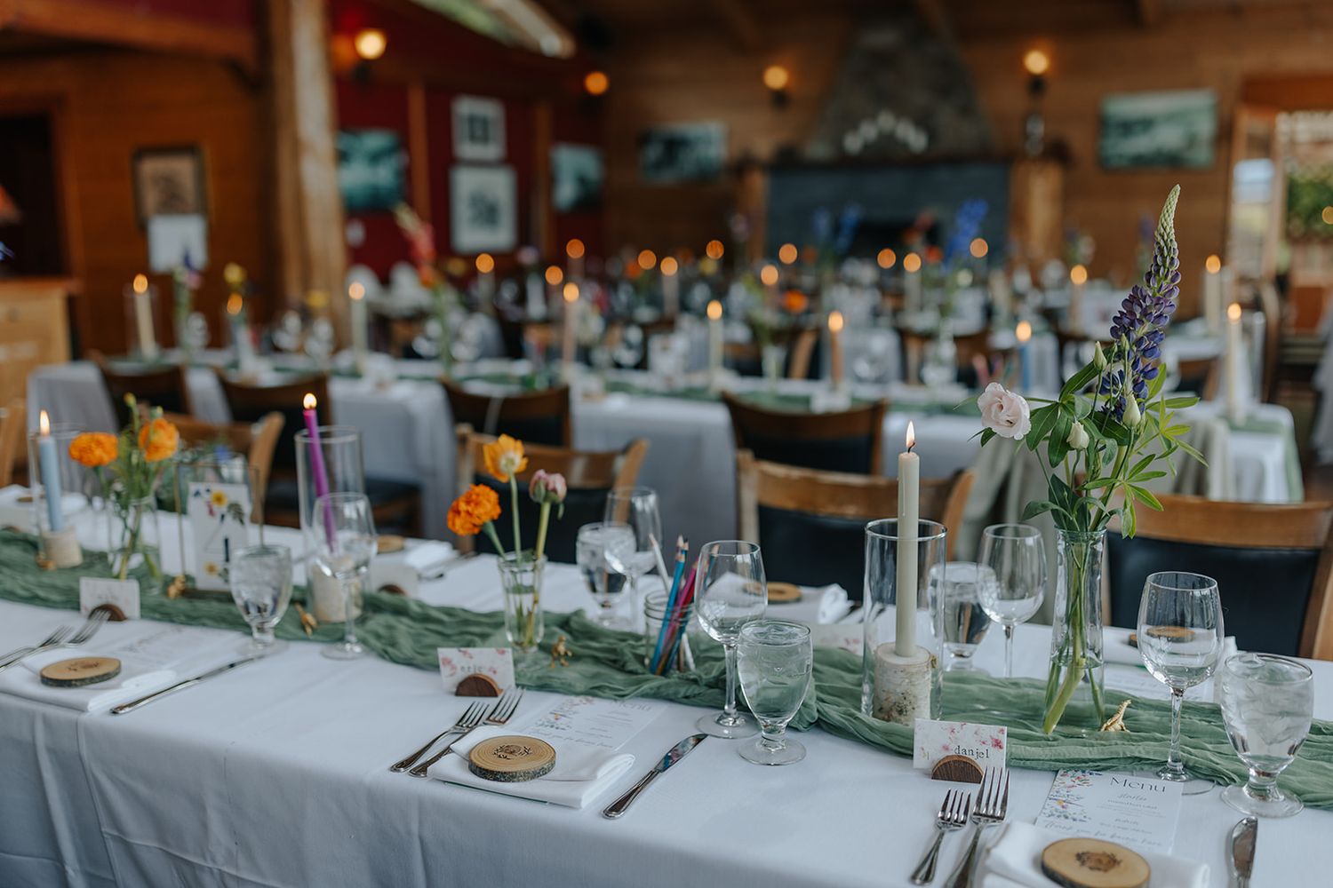 Elegant wedding reception table setting with white linens, floral centerpieces and glassware in a rustic venue.