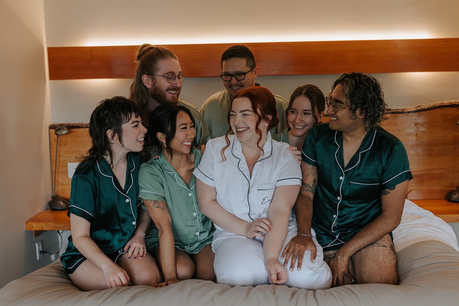 Group of people lounging together on a bed wearing matching robes.