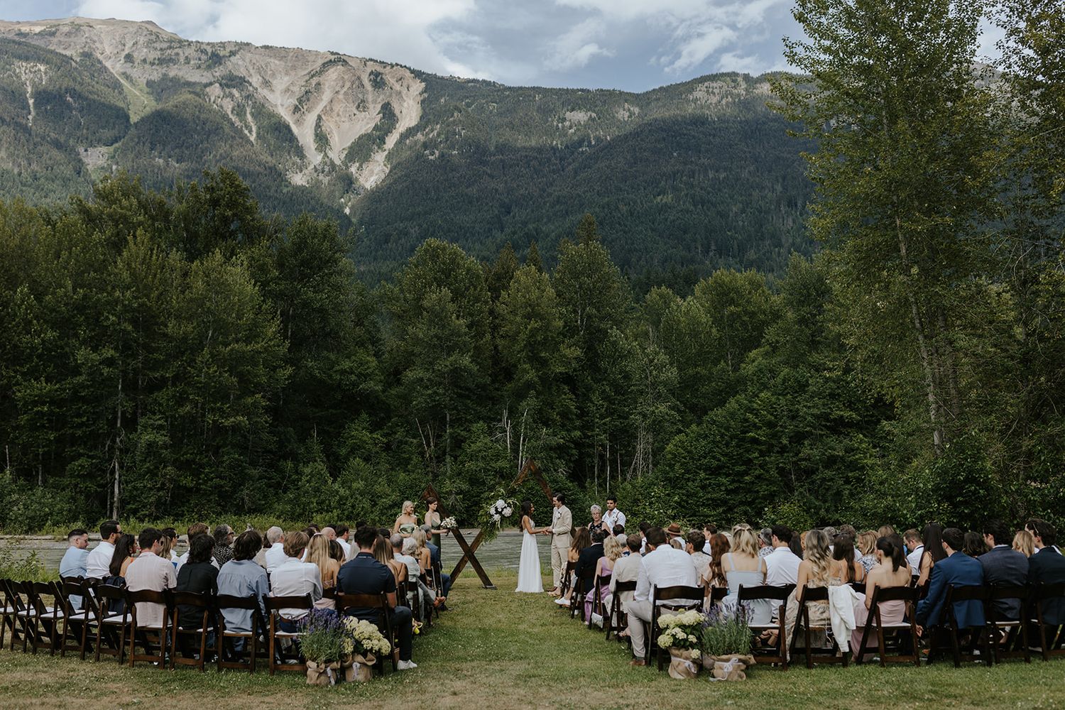 Panoramic mountain landscape serves as backdrop for an outdoor wedding ceremony setup.