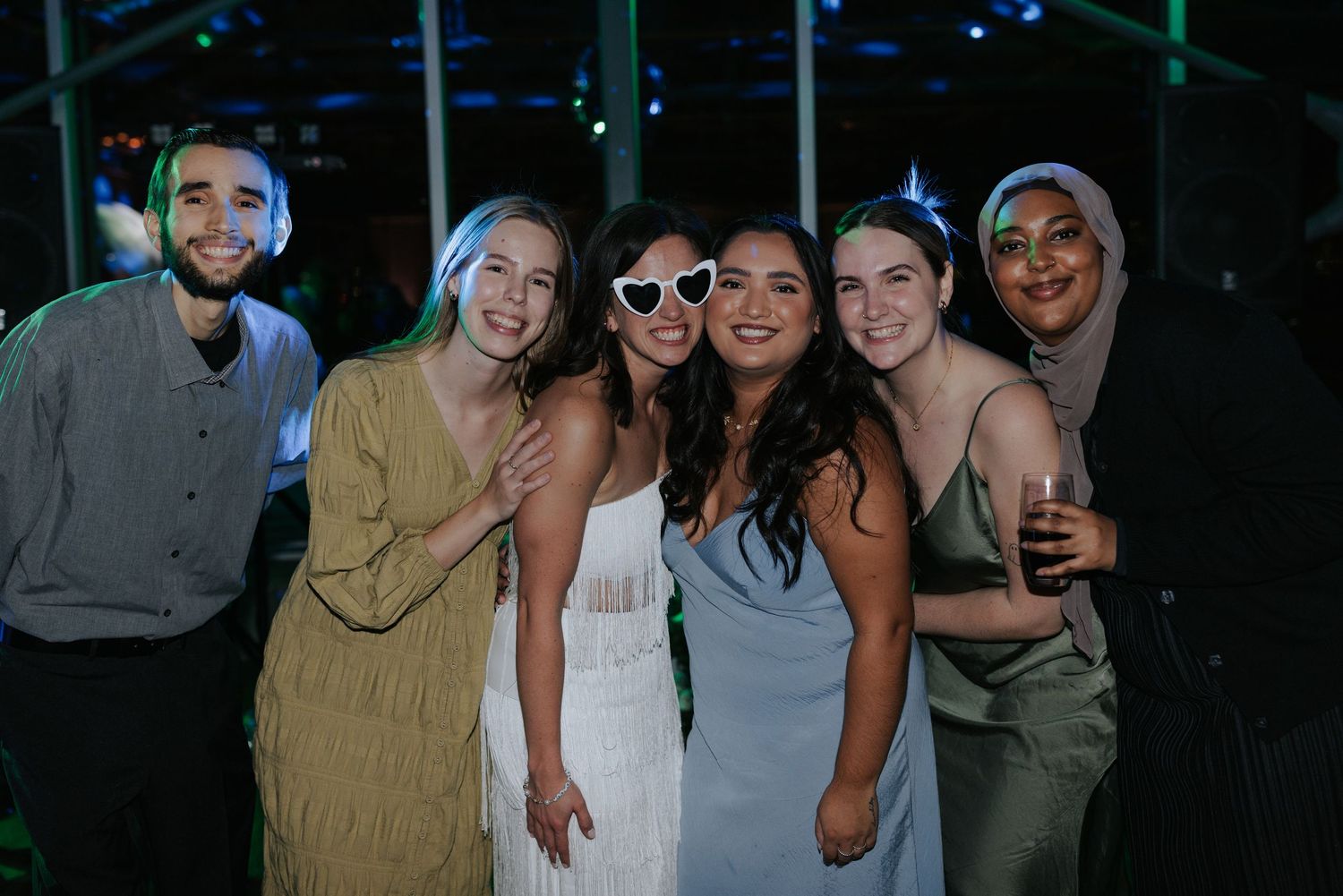 Friends pose together for a group photo during a nighttime wedding celebration.