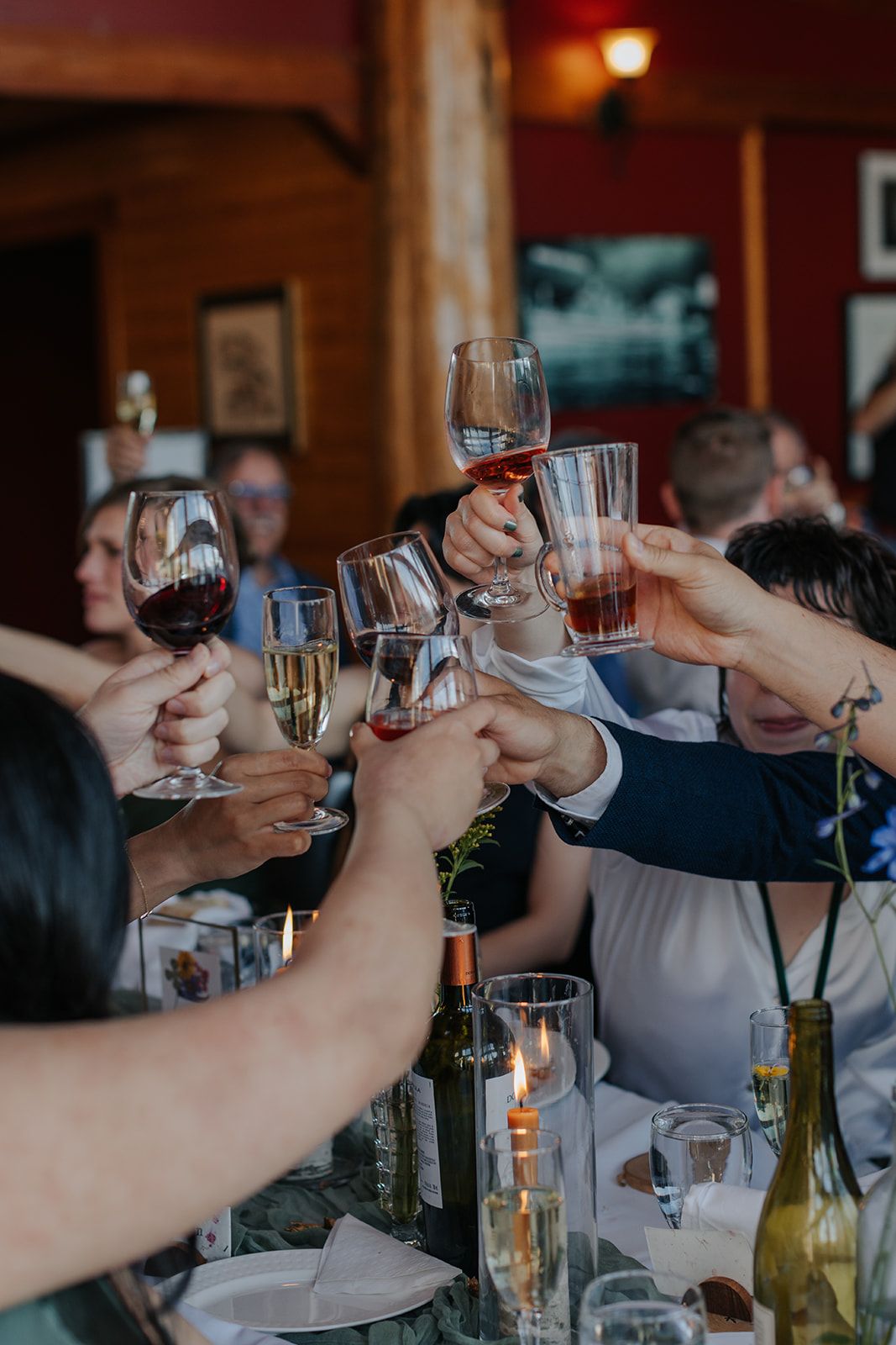 Wedding guests raising glasses in a celebratory toast at reception dinner.