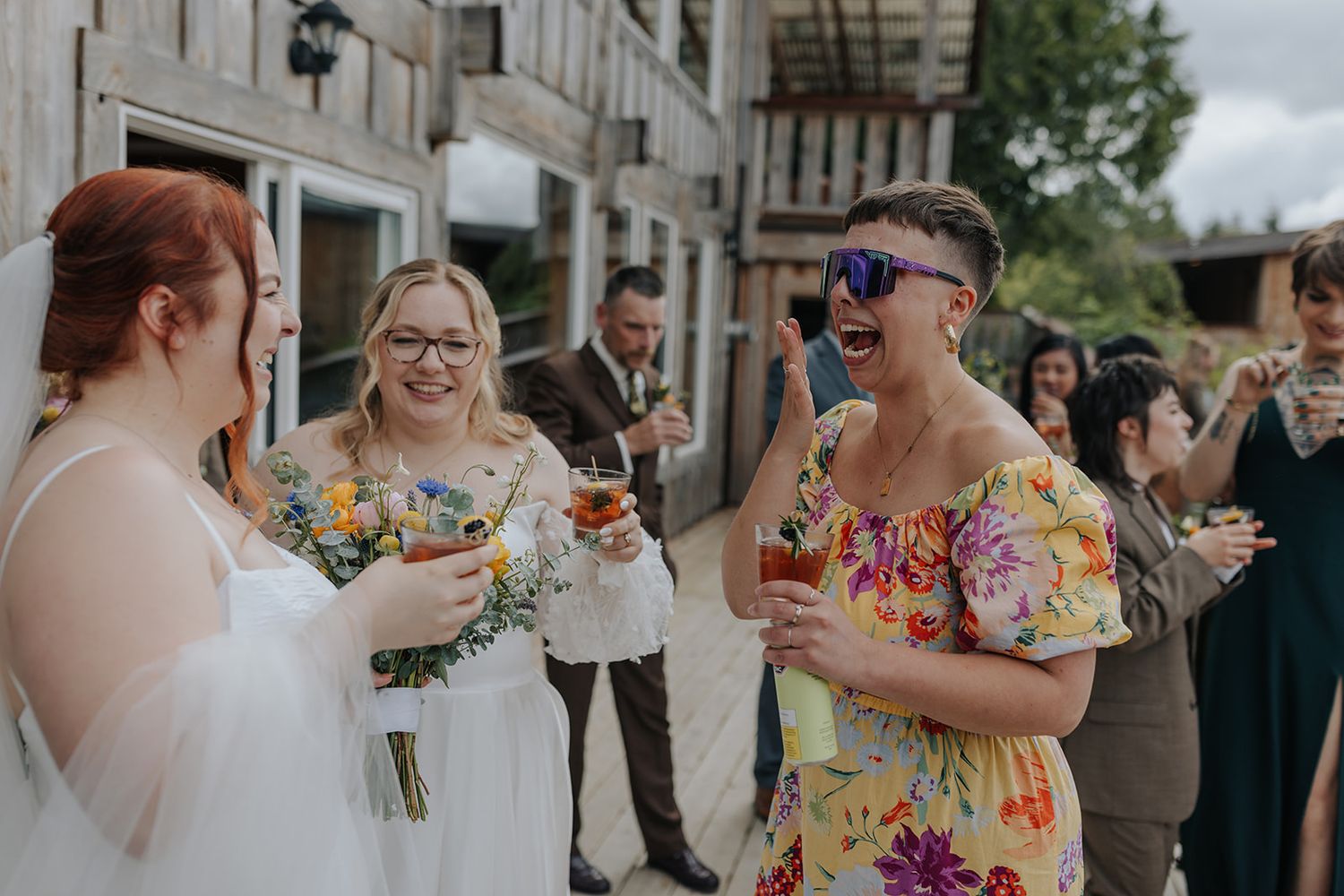 Wedding guests sharing hugs and celebrations outside rustic wooden building.