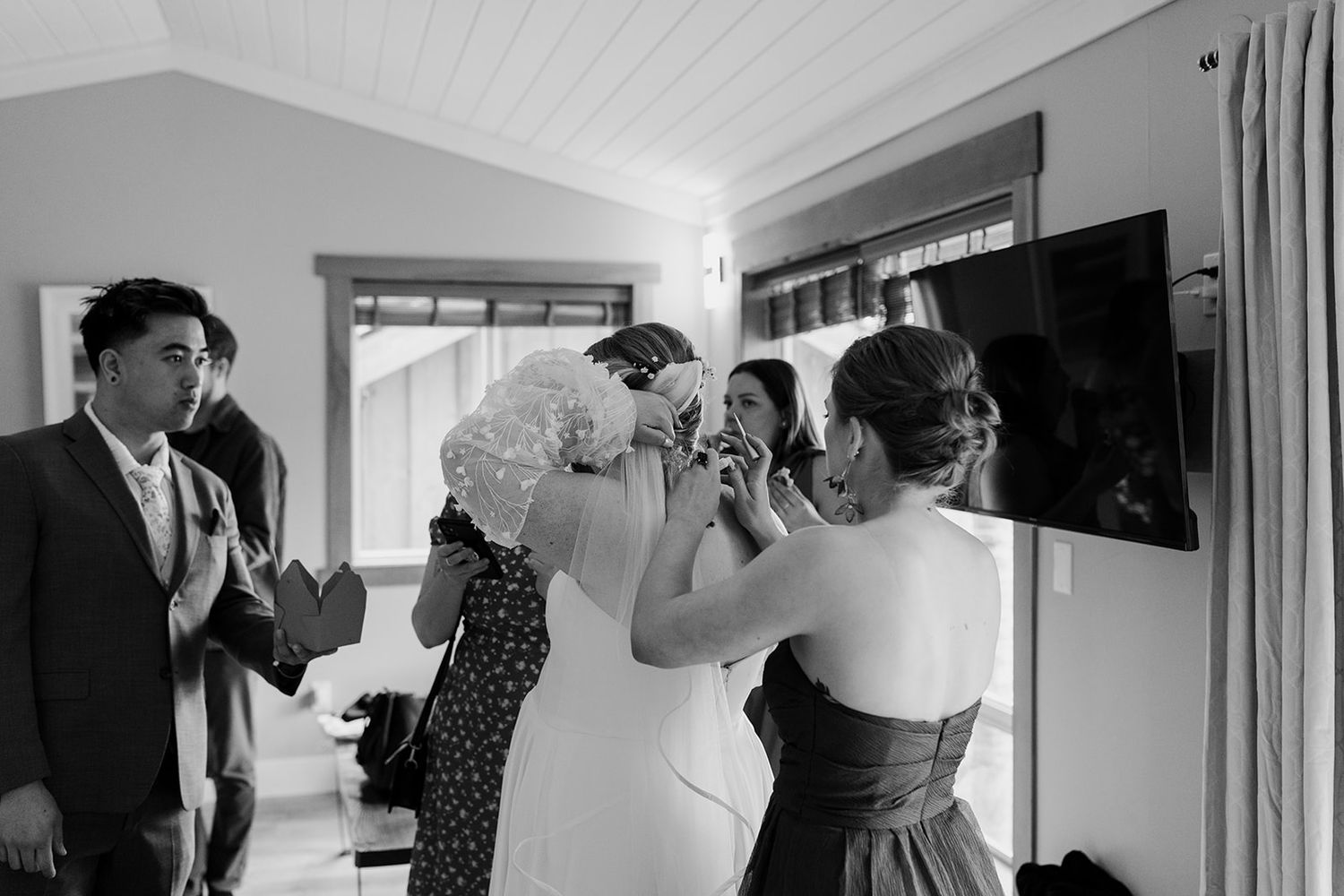 Black and white candid shot of wedding preparation moments indoors.
