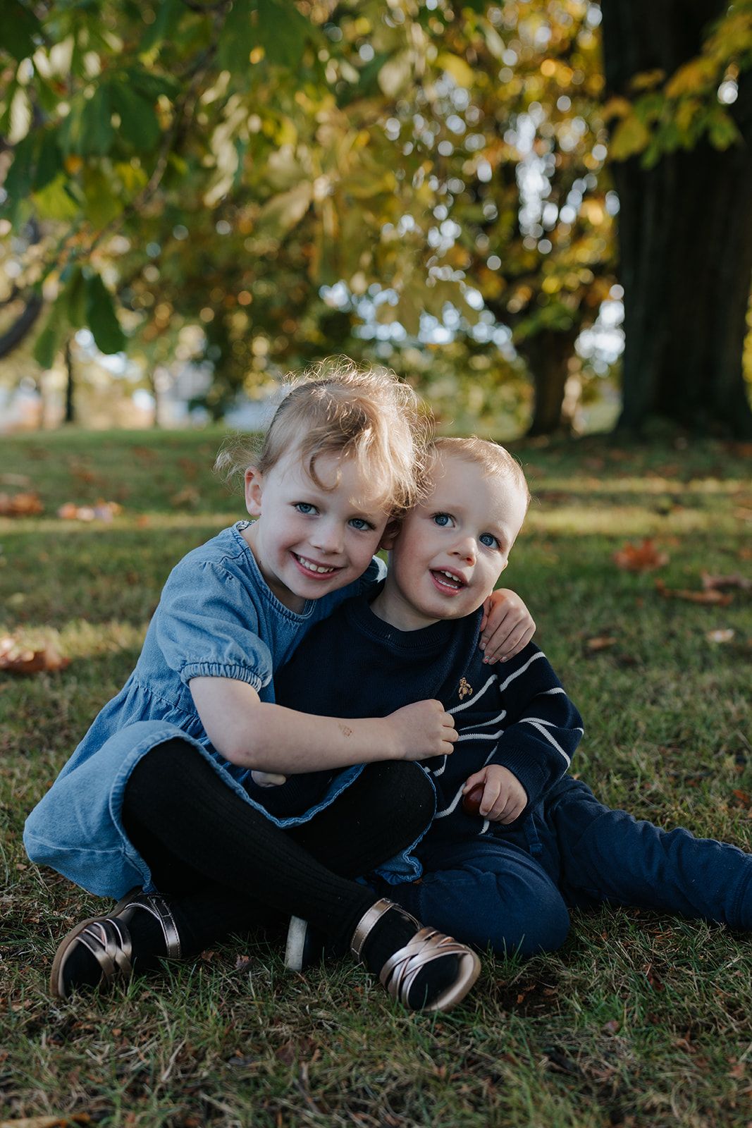 Two children in casual clothing playing and laughing together on grass.