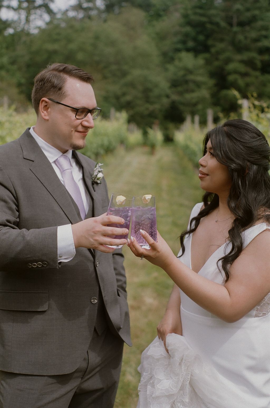 Couple sharing drinks together during wedding celebration in vineyard.