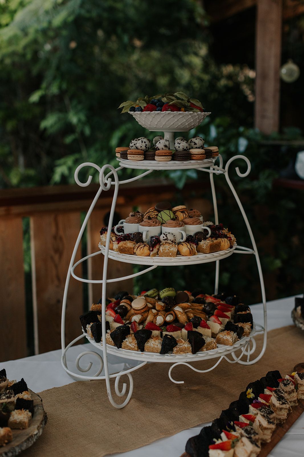 Elegant tiered dessert displays with assorted treats on white metal stands.