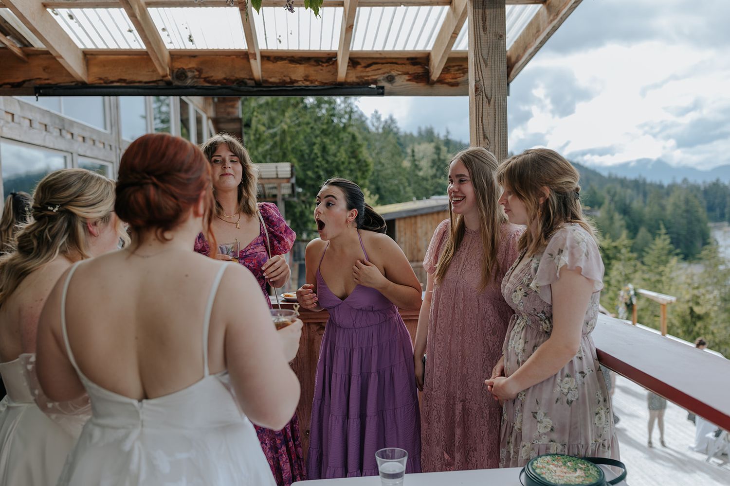Wedding celebration under covered outdoor deck with mountain views in background.