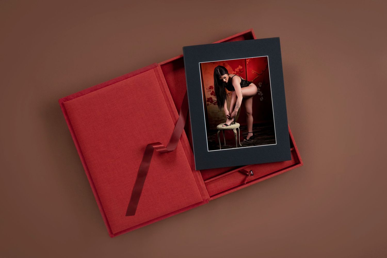 A luxurious red leather photo box with sliding sections displays professional photographs in an elegant presentation.