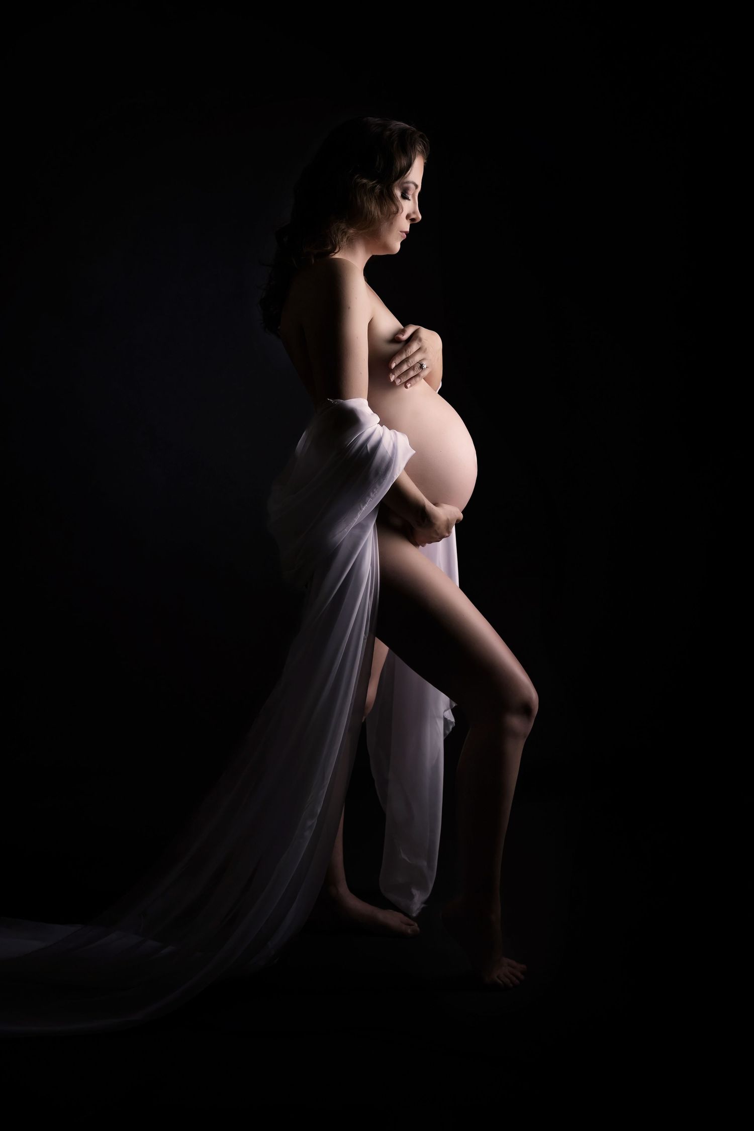 Dramatic maternity portraits with flowing white fabric and moody lighting.