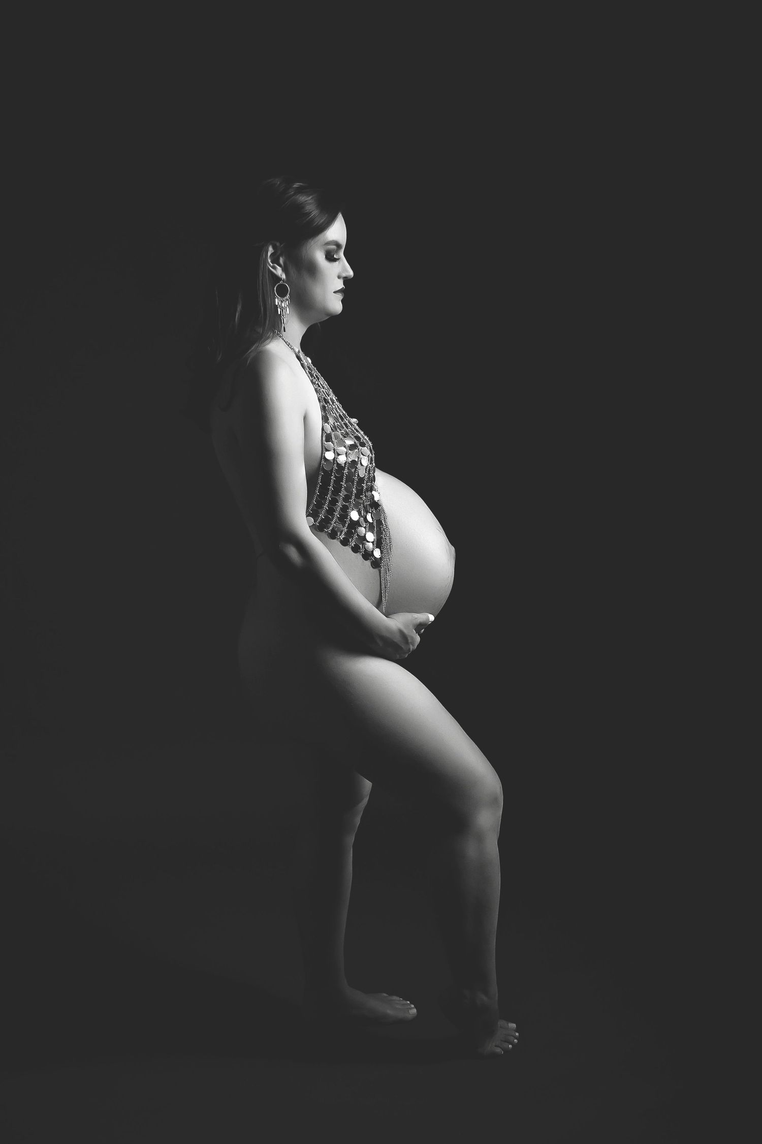 Elegant silhouetted maternity photo showing pregnant profile in dramatic low-key lighting.