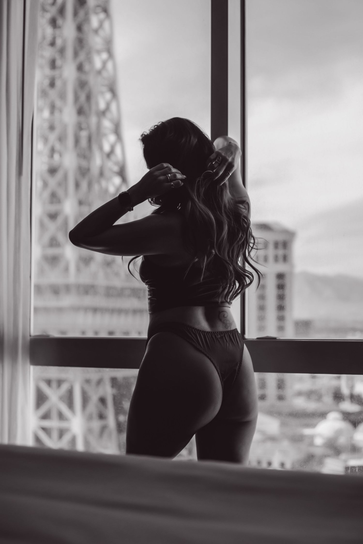 Black and white woman's silhouette photoshoot shows silhouetted figure against windows with geometric patterns in background.