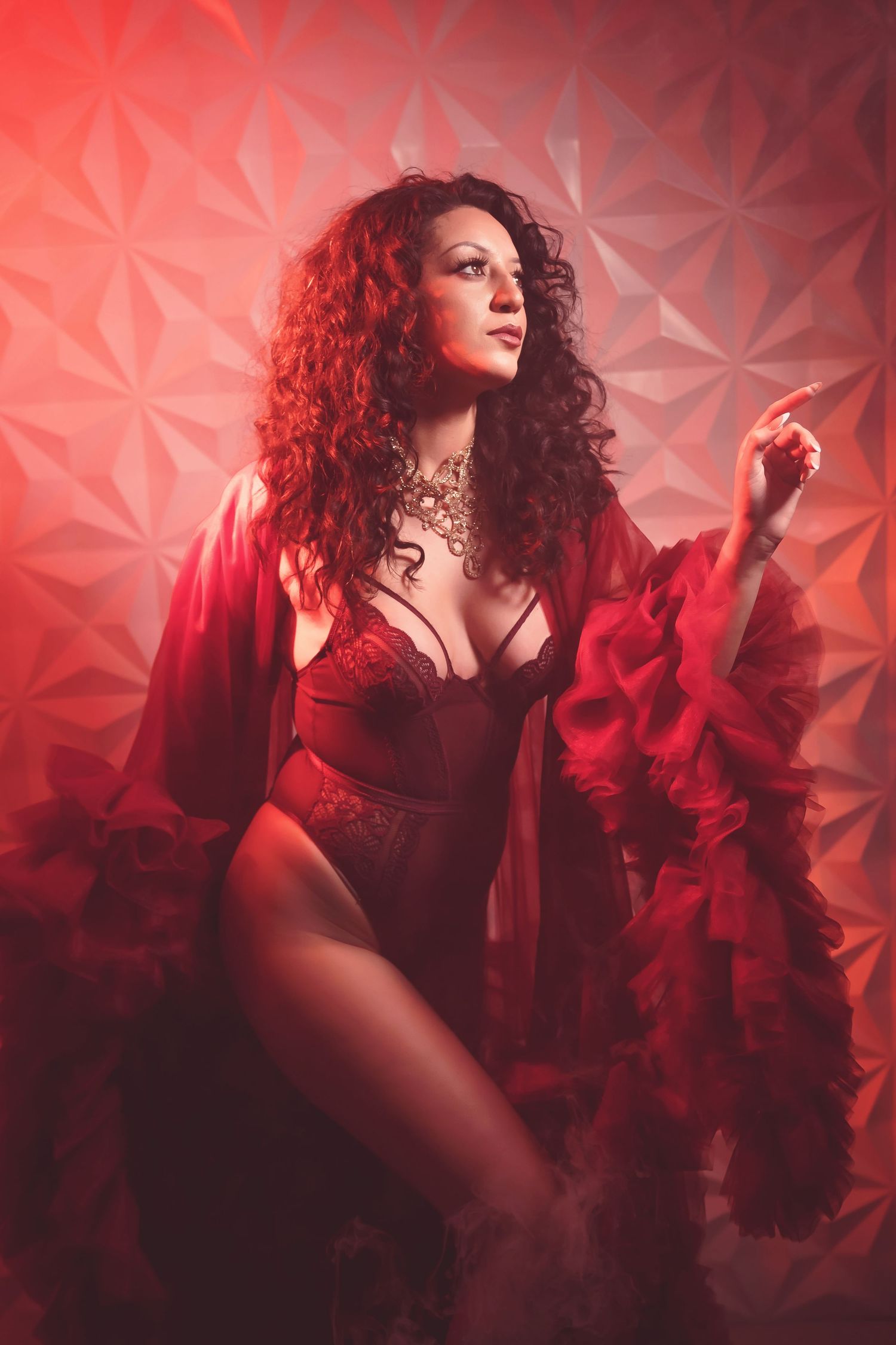 Glamour portrait against textured red wall with dramatic lighting and smoke effects.
