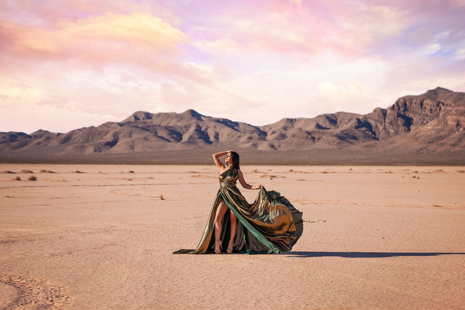 Panoramic desert photoshoot with mountains and dramatic flowing dress.