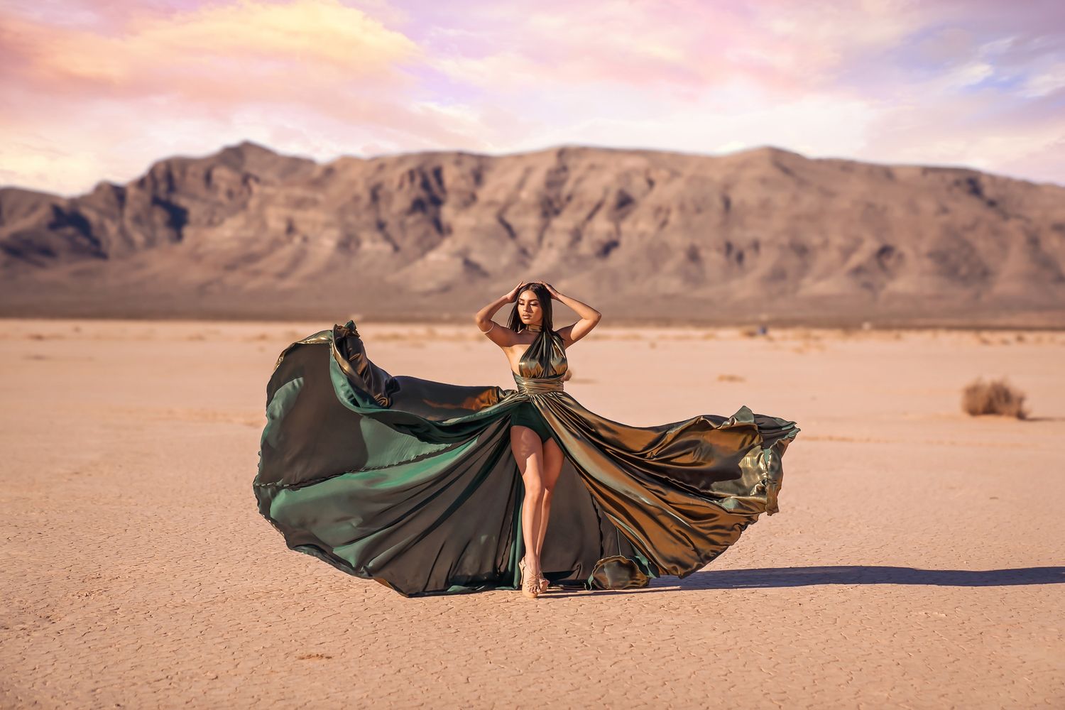 Fashion editorial in desert with billowing emerald dress against mountain backdrop. San Diego glamour photographer