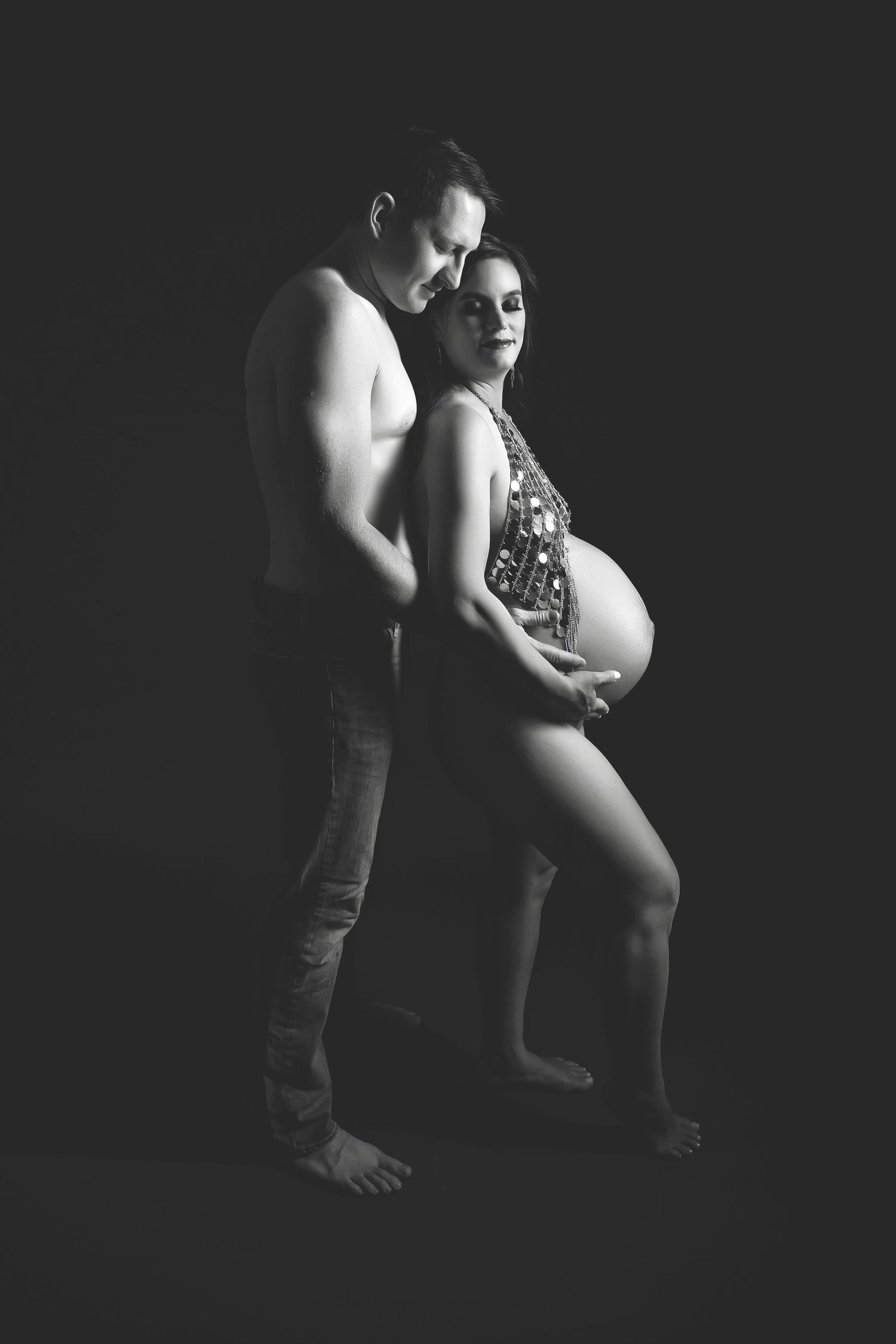 Artistic maternity portrait capturing tender moment between couple in black and white.