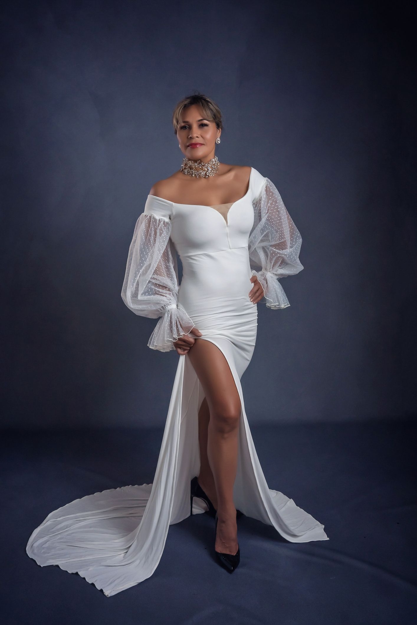 Elegant white flowing dress with dramatic sheer sleeves photographed in a studio setting.