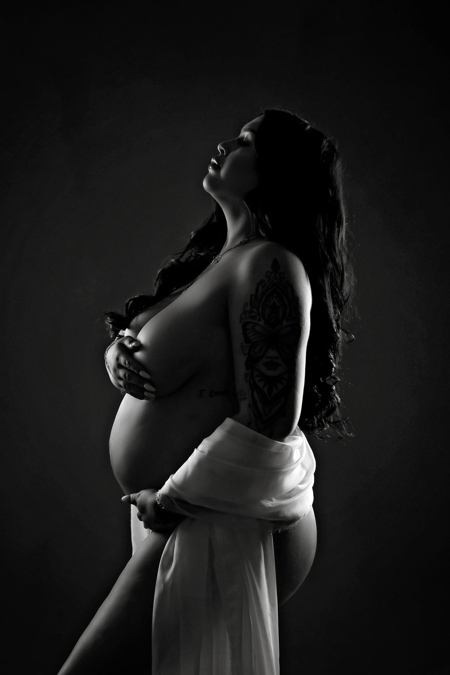 Silhouetted maternity portraits with side lighting against dark background.