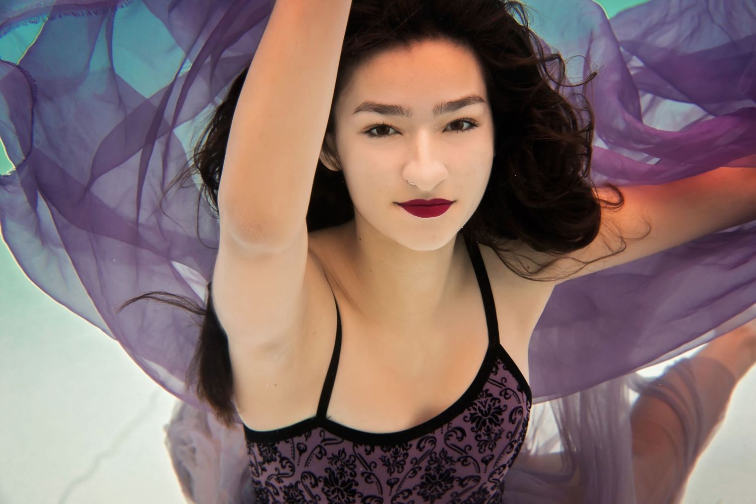 Flowing purple fabric creates dramatic movement in an artistic underwater photo series.
