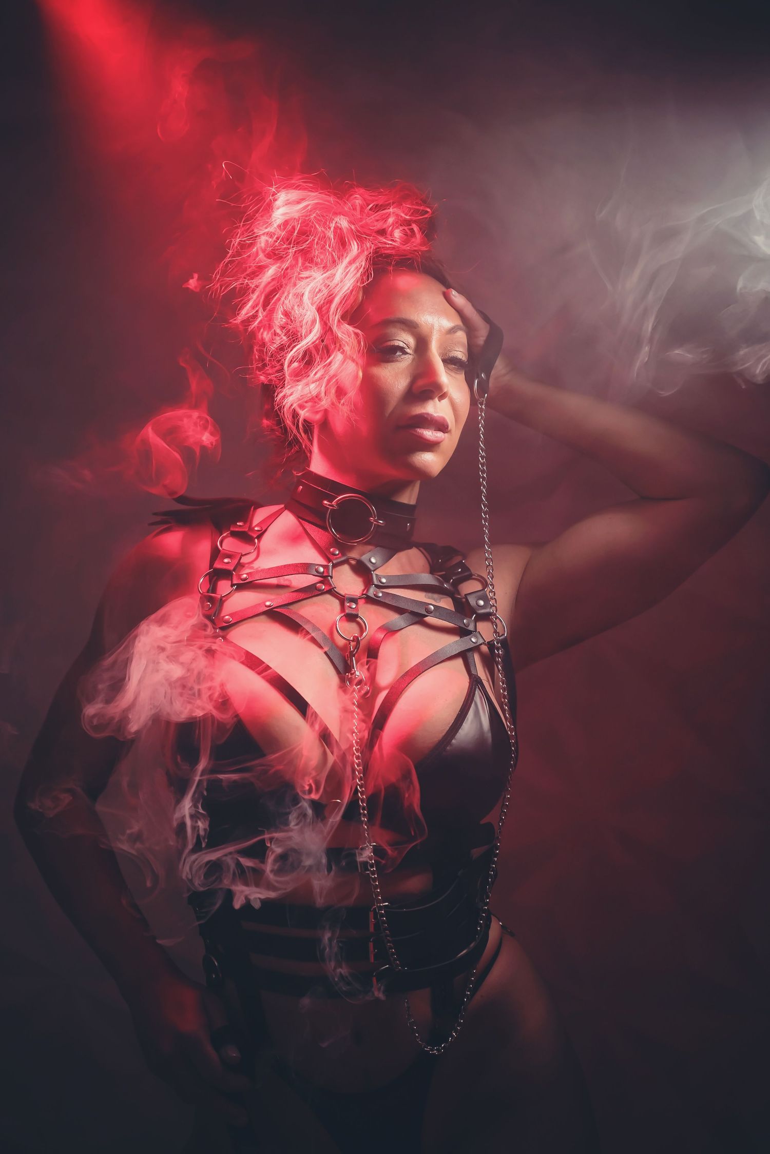 Artistic portrait with glowing red smoke effects and dark shadows creating moody atmosphere.