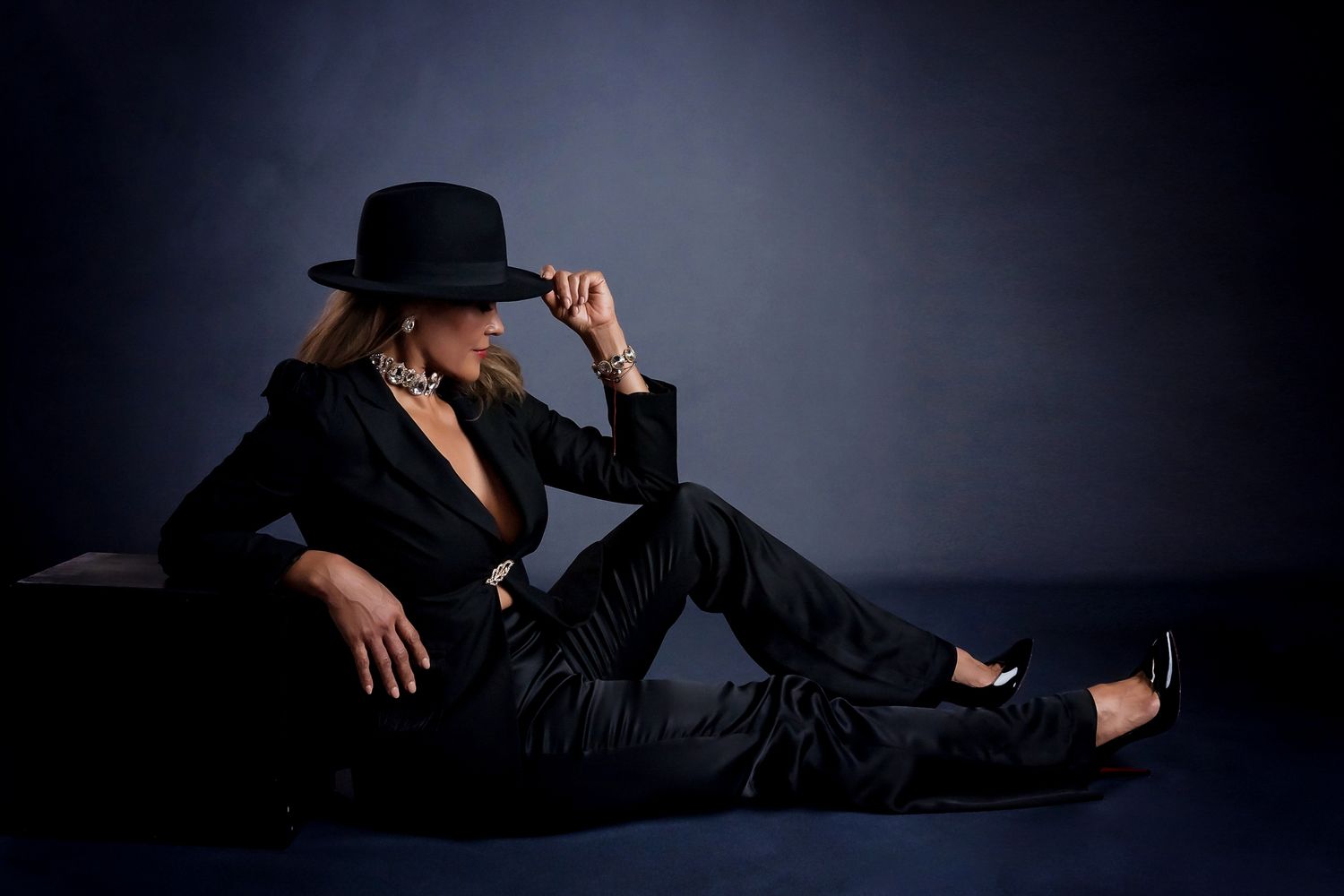 Moody portrait series in dark clothing against blue-toned backdrop.