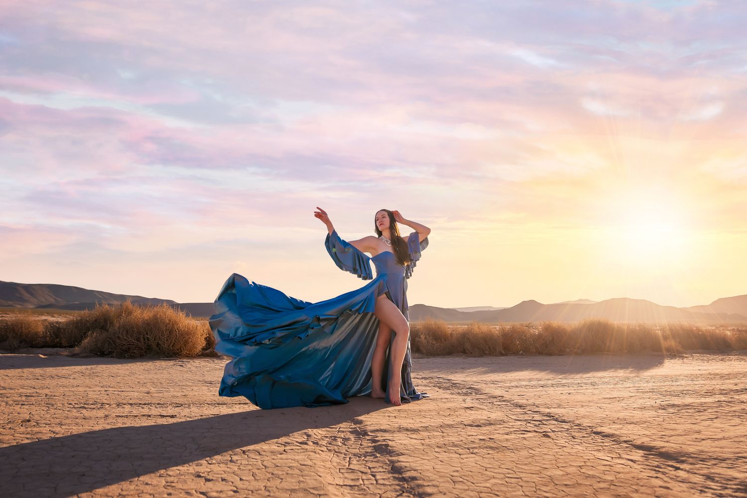 Ethereal desert photography featuring flowing blue dress during golden hour.