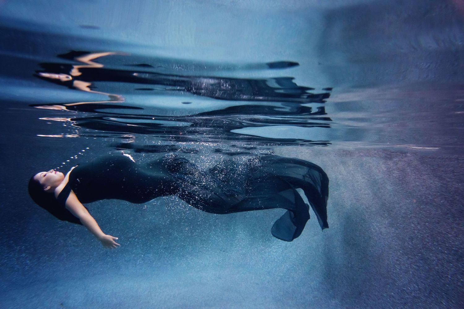 A series of underwater swimmers in a row create a mesmerizing composition with rippling water effects.