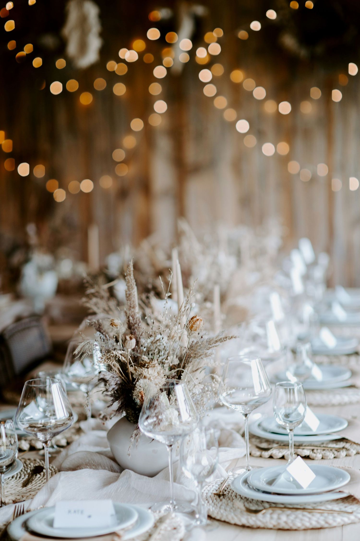 Elegant wedding reception table setting with white florals and candlelight.